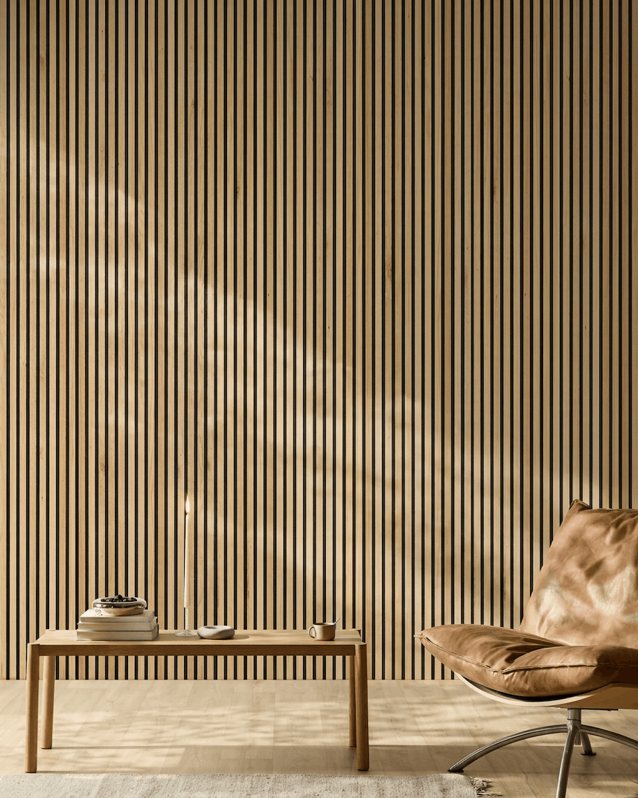 Światło słoneczne oświetla nowoczesne wnętrze z panelem akustycznym WoodUpp Akupanel Panel akustyczny w wykończeniu Rustic Natural Oak na ścianie, obok jasnobrązowego skórzanego fotela i minimalistycznej ławki.
